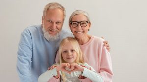 Grandparents and granddaughter share a joyful moment, symbolizing love and family unity indoors.